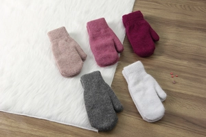 Moffole in maglia rosa, bordeaux e grigio su un tappeto bianco dalla trama densa