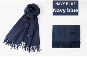 Detail view of navy blue cashmere scarf with fringe trim and brand material label