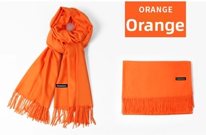 Close-up of bright orange cashmere scarf with tassel edges and branded logo label