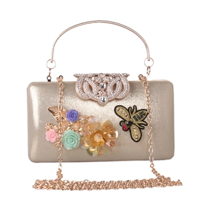 Detailed view of golden evening clutch bag featuring 3D floral accents and bee ornaments