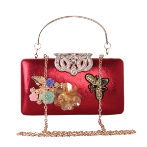Detailed view of red glossy evening clutch with a crystal bee clasp and metal frame