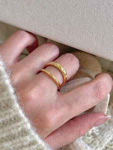 Detail of stacked gold rings featuring smooth band and hammered texture on index finger