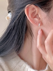 Close-up of minimalist 925 sterling silver hoop earrings and stud on model's ear