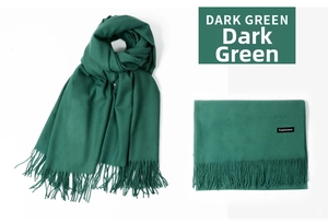 Detail view of dark green cashmere scarf texture with soft fringe and quality labels