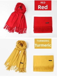 Detail of red and turmeric cashmere scarves featuring soft fringe and woven brand labels