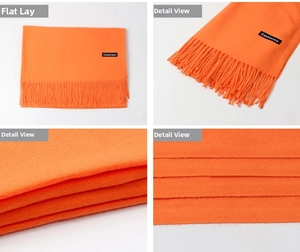 Detail view of orange cashmere scarf showing soft texture, fringes, and weave quality