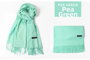 Close-up of pea green cashmere scarf featuring soft tassels and a black logo label