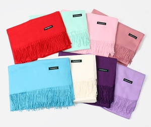 Flat lay of colorful cashmere-feel scarves with fringe tassels and woven labels