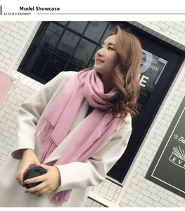 Detail view of pink cashmere knit scarf featuring long fringes and soft wool texture