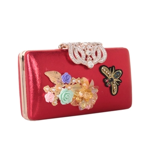 Detail of red evening clutch featuring 3D flowers, bee embroidery and diamond-encrusted clasp