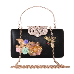 Detail of black evening clutch with 3D floral accents and gold bee embroidery