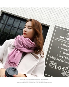 Close-up of light pink cashmere scarf featuring soft tassels and warm knit texture