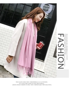 Detail of pink cashmere-like scarf with fringe paired with a white coat for winter