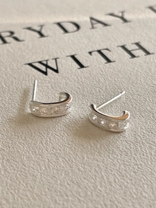 Detail of 925 sterling silver C-shaped stud earrings with inlaid zircon stones