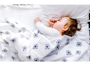 Bébé endormi dans une couverture en mousseline de coton blanche à motifs flocons