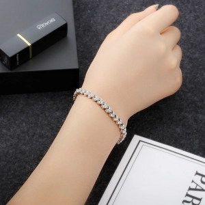 Detailed close-up of a silver-tone tennis bracelet with shimmering heart-shaped links