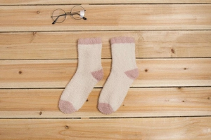 Gros plan de chaussettes en polaire corail moelleuses beige et rose sur fond en bois