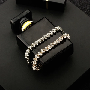 Detailed view of silver and gold heart-shaped crystal bracelets on a luxury perfume bottle