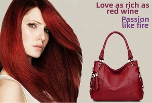 Detail of red faux leather tote bag featuring stitching and decorative side tassel
