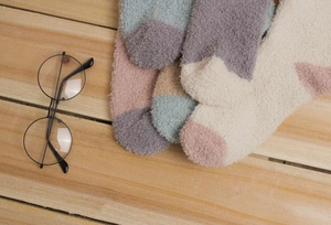 Détail de chaussettes thermiques en polaire corail aux tons pastel sur bois