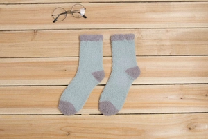Gros plan de chaussettes épaisses en polaire corail bleu clair et violet sur bois