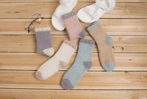 Vue à plat de chaussettes douces en polaire corail aux tons pastels sur fond en bois