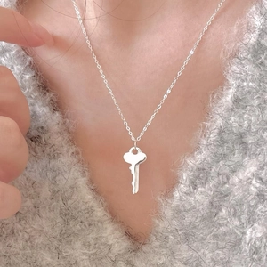 S925 sterling silver key pendant necklace worn by a model over a grey knitted sweater