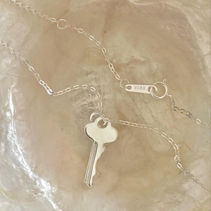 Minimalist S925 sterling silver key pendant necklace on a textured marble background