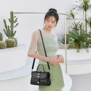 Détail du sac à main en cuir grainé noir avec boucle dorée en forme de cœur chic