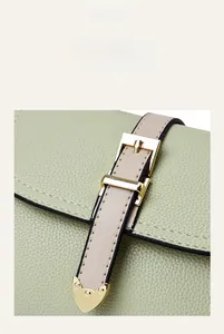 Détail du cuir grainé vert clair avec boucle dorée et finition métallique en forme de cœur