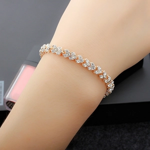 Elegant gold bracelet with white zircons in leaf design shown on a model's wrist