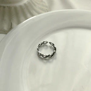 Minimalist S925 sterling silver braided open ring on a clean white ceramic plate