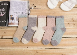 Vue à plat de chaussettes douces en polaire corail en cinq couleurs sur bois rustique