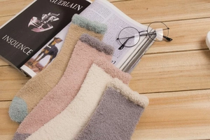 Chaussettes douces en polaire corail aux tons terreux sur une table en bois avec magazines
