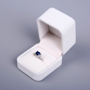 Detail view of a heart-shaped sapphire ring inside a premium white velvet jewelry box