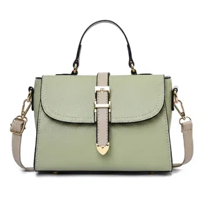 Vue détaillée du sac à main vert clair montrant la texture cuir et le fermoir en cœur