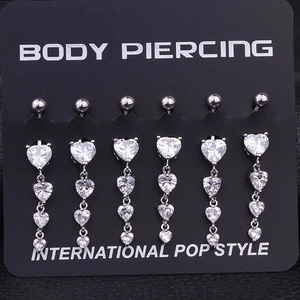 Close-up of six silver heart-shaped zircon dangle belly rings on body piercing display card