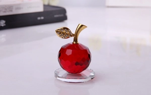 Dettaglio di mela in cristallo rosso con foglia di strass dorata e base trasparente