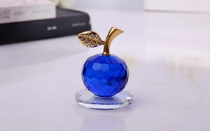 Dettaglio di mela in cristallo blu con stelo dorato e strass su base trasparente