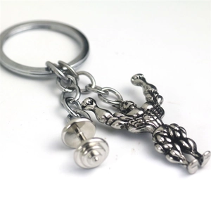 Detailed close-up of a silver muscular man keychain with a small dumbbell charm