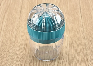 Close-up of manual citrus juicer with turquoise reamer on a natural wooden surface