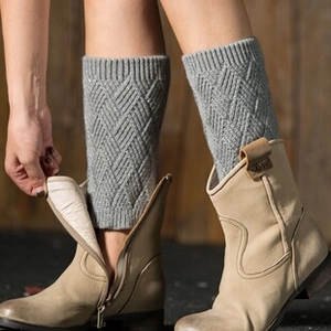 Detailed knit pattern of grey diamond-textured leg warmers paired with beige boots