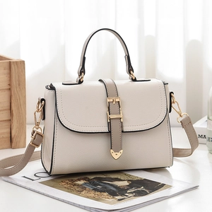 Sac à main élégant en cuir crème avec bandoulière grise et détails dorés sur fond bois