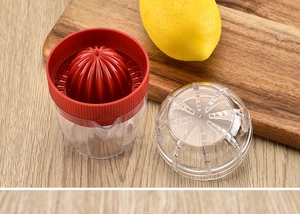 Manual lemon squeezer set with red cone and clear cup on a wooden background