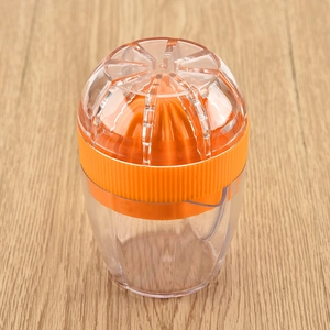 Manual orange juicer with a ribbed head and transparent cup on a wooden table