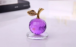 Dettaglio macro della mela in cristallo viola con foglia d'oro e diamanti su base rotonda