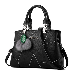 Elegant black lychee leather handbag with white geometric stitching and furry pendant decor