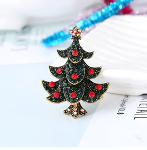 Macro shot of vintage gold Christmas tree brooch with sparkling red and green crystals