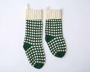 Détail de deux chaussettes de Noël en tricot vert avec des pois blancs et revers côtelés