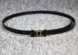 Détail de ceinture fine noire en cuir avec boucle nœud dorée et trous de réglage